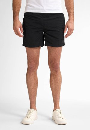 Schwarze Badeshorts mit flexiblem Bund und einem kleinen Logodetail. Hergestellt aus leichtem Stoff, sind sie knielang und leicht strukturiert.