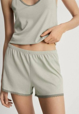 Helles grünes Baumwoll-Top mit Spitzenbesatz. Die passenden Shorts haben einen elastischen Bund und zarte Spitze am Saum. Weicher Stoff.