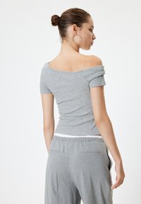 Harmaa ribbipintainen, olkapäiltä avoin paita lyhyillä hihoilla, istuva muotoilu, yhdistetty vaaleanharmaisiin raidoitettuihin housuihin. Yksinkertainen valkoinen joustovyötärö.