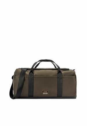 Prostokątny torba podróżna w kolorze oliwkowej zieleni z czarnymi uchwytami i paskiem na ramię, z przednią metką z napisem "Ochnik Riders Supply Custom Built".