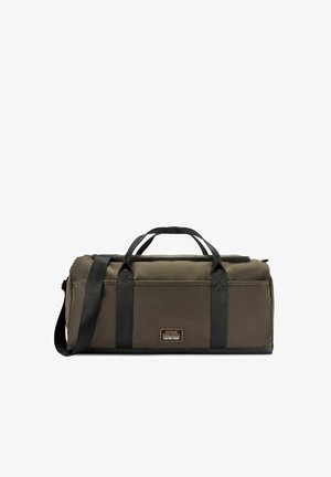 Prostokątny torba podróżna w kolorze oliwkowej zieleni z czarnymi uchwytami i paskiem na ramię, z przednią metką z napisem "Ochnik Riders Supply Custom Built".