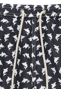 Costumi da bagno realizzati in tessuto leggero, con uno sfondo nero e un motivo ripetitivo di squali bianchi, e cordino beige.