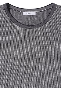 S/w kleine gepunktete Strickware eines Crew-Neck-Shirts mit einem "Cecil"-Label im Kragen.