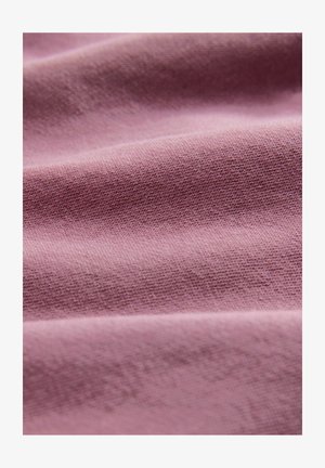 Tela de color rosa claro con una textura suave. La superficie presenta variaciones sutiles, incluyendo un tejido fino y un ligero brillo.