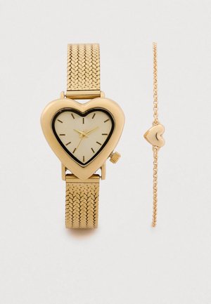 Guldur med hjerteformet urskive med mesh-armbånd, sort kant og lysebeige urskive, ledsaget af et matchende guldkædearmbånd med hjerte-detalje.