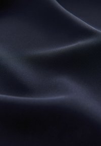 Hladká, tmavě modrá látka s jemným leskem a jemně proužkovanou texturou, která předvádí něžné záhyby a měkké splývání.