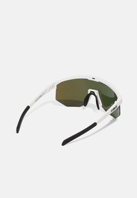Occhiali da sole sportivi con una montatura bianca e lenti esagonali verdi. Astine nere e marchio sul lato. Design moderno.