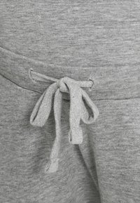 Grijze trekkoord gemaakt van zachte, gestructureerde stof met een gestrikte strik, bevestigd aan de tailleband van een kledingstuk.