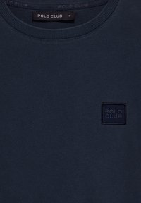 Granatowa bluza crewneck wykonana z bawełny, z kwadratową granatową łatą z logo "POLO CLUB" na przodzie. Gładka faktura i żebrowany dekolt.