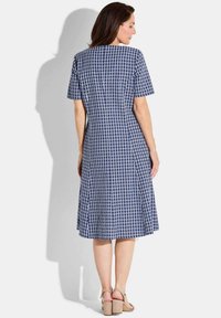 Navy-blaues kariertes Kleid mit kurzen Ärmeln, tailliertem Oberteil und ausgestellt Rock, aus leichtem Stoff gefertigt. Es hat einen runden Halsausschnitt und Seitennähte.