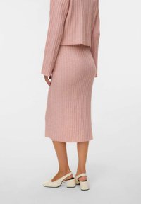 Lyserød ribbet strikket to-delt sæt bestående af en cropped top og en knælængde nederdel, parret med cremede slingback sko med blokhæle.