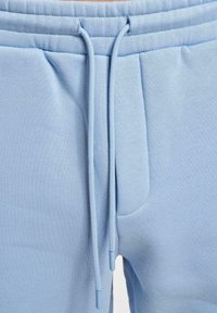 Lichtblauwe sweatpants van een zachte, gestructureerde stof. Voorzien van een elastische tailleband met een trekkoord en zijzakken.