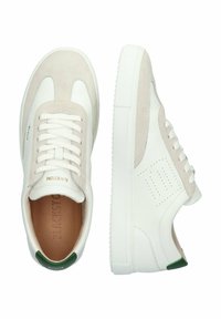 Zapatillas blancas de cuero con acentos de ante beige claro, punta redondeada, suela de goma texturizada y una lengüeta trasera verde. Presenta un diseño perforado en el lateral.
