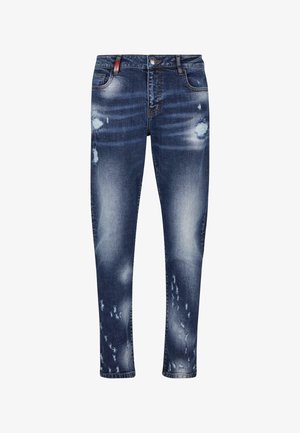 Jeans de mezclilla azul de corte ajustado con parches desgastados y decoloración. Cuenta con cinco bolsillos y cierre de botón. Tejido lavable a máquina.