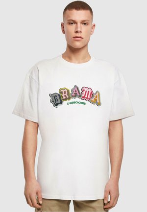 T-shirt en coton blanc avec un grand texte multicolore « DRAMA » dans différentes polices et la phrase « I CHOOSE » en vert en dessous. Manches courtes, coupe décontractée.