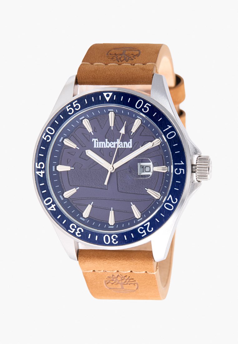 Timberland horloge met een marineblauwe wijzerplaat, zilveren kast en brown leren band. Kenmerken zijn onder andere een datumaanduiding en urenmarkeringen in de vorm van pijlen.