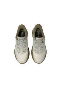 Un paio di sneaker beige Skechers slip-on con tomaia in rete, lacci elastici e suole marroni viste dall'alto su sfondo bianco.