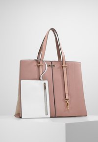 Sac fourre-tout en cuir rose avec double poignée et pochette rectangulaire blanche attachée, dotée d'une poche zippée à l'avant, présenté sur une surface blanche.