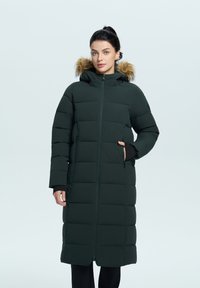 Dlouhá zelená péřová bunda se zipem, předními kapsami a odnímatelnou kapucí s kožíškem. Má prošívaný design a černé manžety.