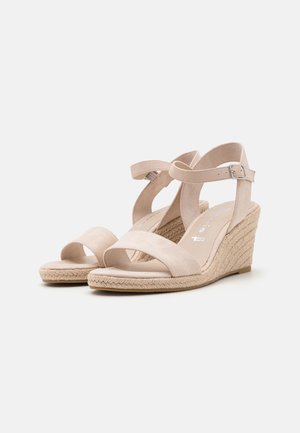 Beige Wedgesandalen mit einer weichen Wildleder-Oberfläche, ausgestattet mit zwei breiten Kreuzriemen und einem verstellbaren Knöchelriemen, auf einer geflochtenen Jute-Sohle.