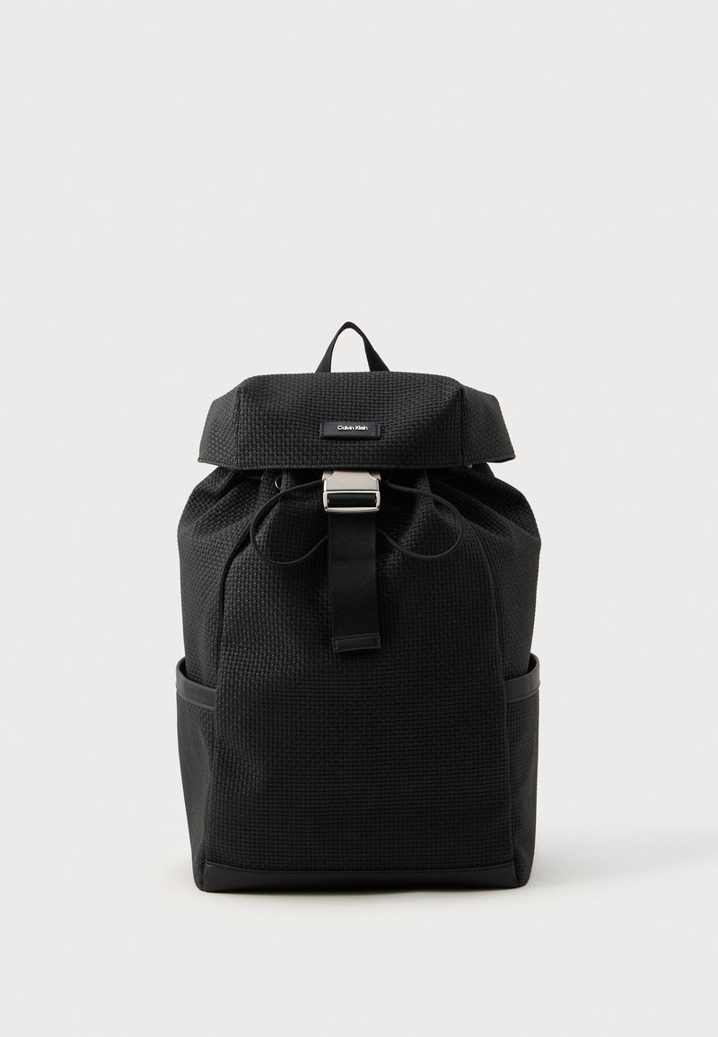 Crna ruksak napravljena od teksturirane tkanine, s preklopom, podešivim trakama, prednjim kopčanjem i bočnim džepovima.
