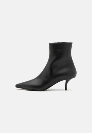 Črne usnjene gležnjarje s koničastim nosom, elegantno silhueto in tankim, ukrivljenim peto. Gladka tekstura in minimalističen dizajn.