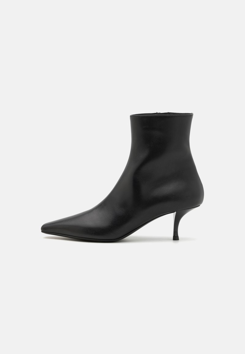 Botas de tornozelo em couro preto com bico fino, silhueta elegante e um salto fino e curvado. Textura suave e design minimalista.