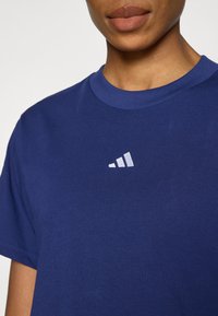 Tengerészkék pamut póló kerek nyakkivágással. A mellrészen fehér dombornyomott logóval díszített. Simább tapintású, rövid ujjú.