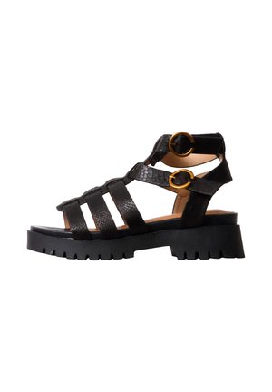 Zwarte sandalen met bandjes, dikke grof profielzool, twee gouden gespen en een gestructureerd leren bovenwerk zijaanzicht.