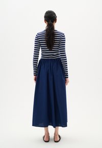 Top à manches longues rayé bleu marine et blanc, associé à une jupe maxi unie bleu marine. Tissu en coton, taille élastique et silhouette fluide.