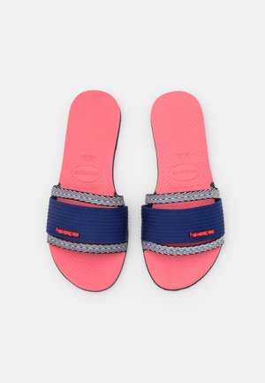 Paire de sandales à semelle rose avec des brides en tissu rayé bleu marine et blanc, avec le logo rouge "havaianas" sur chaque bride.