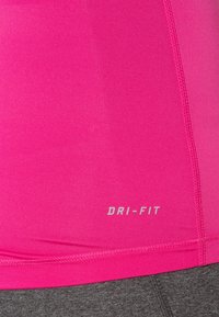 Bright pink athletic fabric with visible stitching details and "DRI-FIT" printed in light gray near the hem, paired with dark gray fabric below.