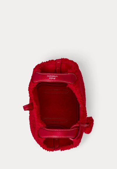 Červená kabelka z ovčí vlny s koženými doplňky, zaobleným tvarem, horními uchy a měkkou vnitřní podšívkou. Na vnit�řní podšívce je logo.