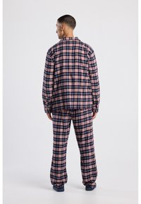 Navy and red plaid pajama set made of soft fabric. Oversized shirt with a collar and matching loose-fitting pants, both featuring check pattern.