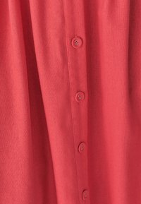 Koronowy krótki rękaw koszula zapinana na guziki, wykonana z fakturowanej tkaniny, z pionowym rzędem sześciu guzików na przodzie.