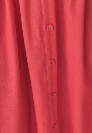 Koraalkleurig overhemd met knoopsluiting, gemaakt van een gestructureerde stof, met een verticale rij van zes knopen aan de voorkant.