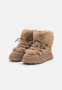 Beige Kunstfell-Ankle-Boots mit dicker Sohle, gerafftem Design und schnürbarem Vorderteil. Besitzen ein weiches Futter und eine abgerundete Zehenform.