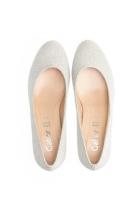 Bailarinas brillantes plateadas con punta redondeada y suela acolchada. Parte superior de tela suave y diseño minimalista. Nombre de la marca visible en el interior.