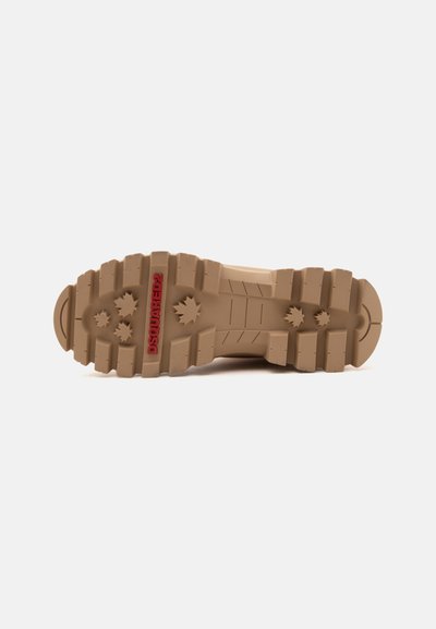 Semelle crantée d'une botte beige avec des rainures profondes et des motifs en forme d'étoile, avec le marquage "DSQUARED2" en rouge.