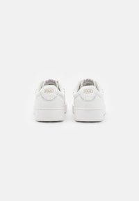 Sneaker bianche con tomaia in pelle liscia, suola spessa bianca e logo embossato discreto sul tallone. Design con lacci e colletto imbottito.