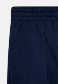 Mörkblå joggerbyxor tillverkade av en bomullsblandning, med elastisk midja, sidofickor och en slät yta.