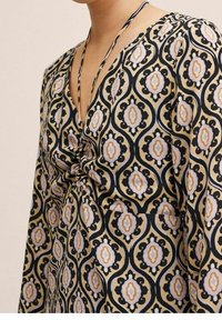 Monivärinen mekko, jossa on kukkakuosi ja geometrinen kuvio, V-pääntie ja solmittavat hihnat, valmistettu kevyestä kankaasta, jolla on pehmeä rakenne.