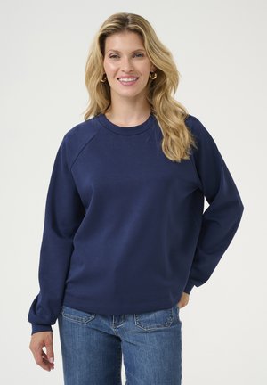 Navy blue sweatshirt with a crew neckline, raglan sleeves, and soft texture. Paired with light blue jeans, minimal details, and no patterns.