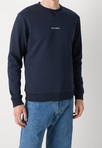 Felpa navy in morbido cotone con polsini e scollatura a costine, presenta la scritta "LES DEUX" in bianco al centro. Abbinata a jeans.
