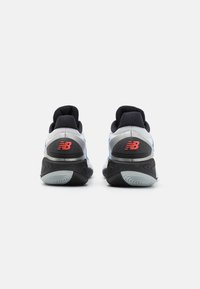 Athletic shoes with a gray and blue mesh upper, black textured sole, and red New Balance logo on the heel. Comfortable cushioning design.