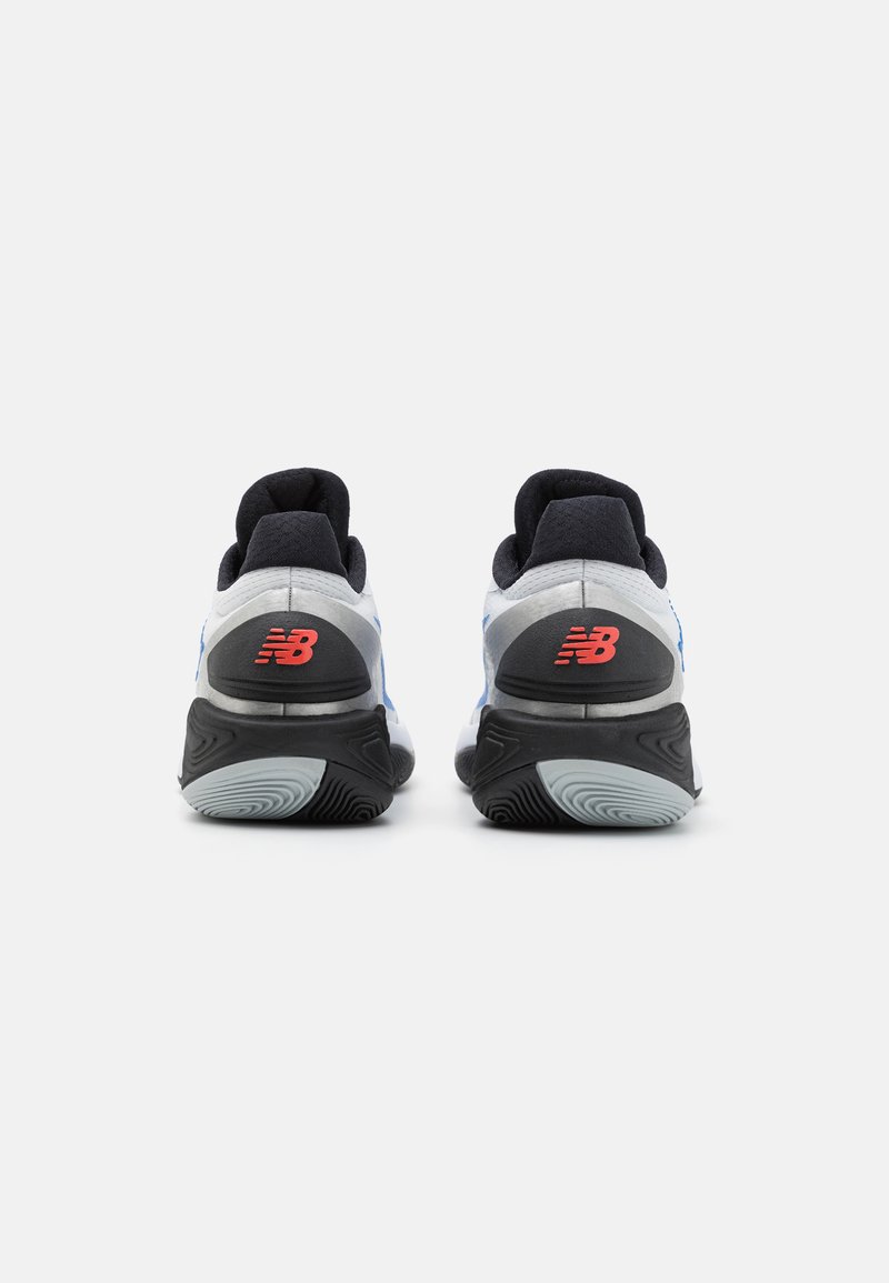 Zapatillas deportivas con una parte superior de malla gris y azul, suela texturizada negra y logotipo rojo de New Balance en el talón. Diseño de amortiguación cómodo.