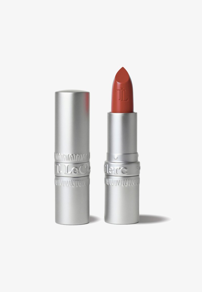 Lippenstift in einer silbernen Metalltube mit strukturierten Akzenten. Der Farbton ist ein matter, gedämpfter rötlich-brauner Ton. Die Tube ist leicht angehoben mit einer abgerundeten Spitze.