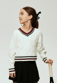 Baltas megztinis su pynimo raštu ir V formos iškirpte, papuoštas bordo ir juodomis juostelėmis. Derinamas su juoda klostuota suknele ir laiko teniso raketę.