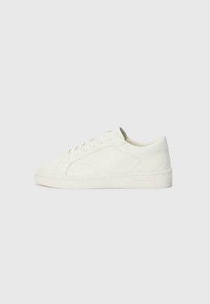 Baskets en cuir blanc avec une texture lisse, bout rond, fermeture à lacets à six œillets et semelle en caoutchouc légèrement surélevée.