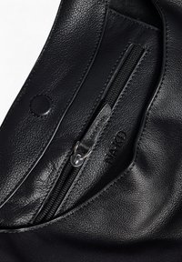 Sort lædertaske med en tekstureret overflade, en lynlåslomme og en trykknaplukning. Designet er enkelt og funktionelt.